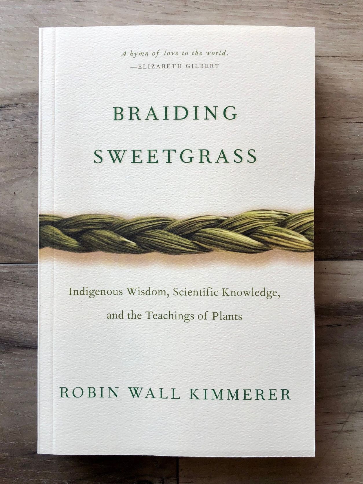 Book cover for Robin Wall Kimmerer's Braiding Sweetgrass. Book cover is on a white background, and a braid of sweetgrass is featured horizontally across the center of the page.