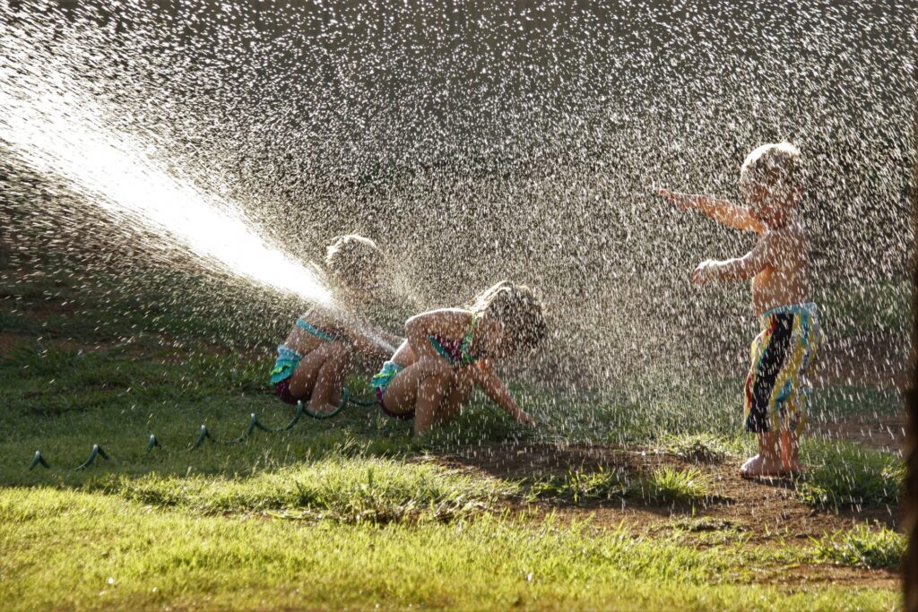children playing outside in a water sprinkler
