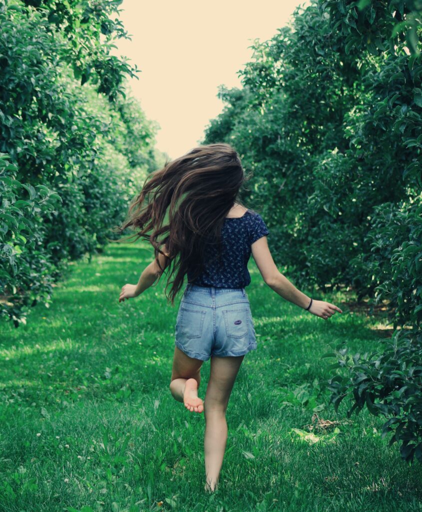 Girl runs outside through trees