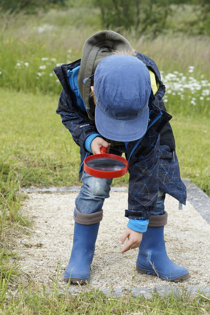 Boy studies the ground with a magnifying glass