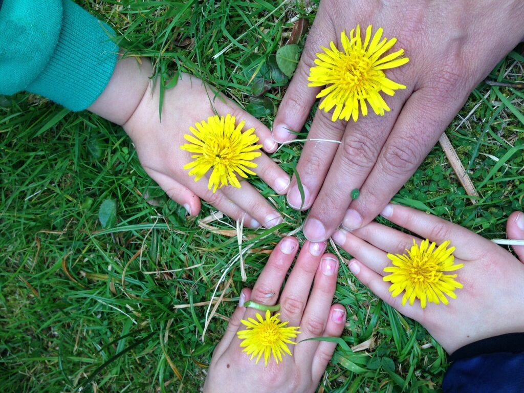 Family members place hands on ground holding dandelions