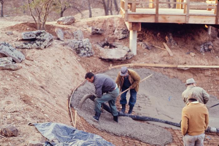 Workers pour concrete in the Japanese Garden pond under construction